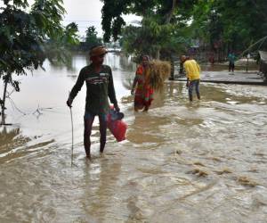 Los aldeanos caminan a través de las aguas de la inundación después de las fuertes lluvias en el distrito de Hojai, estado de Assam, el 21 de mayo de 2022.