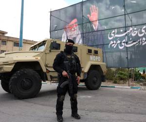 Un miembro de las fuerzas de seguridad iraníes monta guardia junto a una pancarta en honor al exlíder supremo iraní Ali Jamenei, en Teherán, Irán.