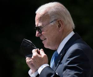 En esta foto de archivo tomada el 27 de julio de 2022, el presidente de los Estados Unidos, Joe Biden, se quita la máscara protectora mientras llega para pronunciar declaraciones en el jardín de rosas de la Casa Blanca en Washington, DC.