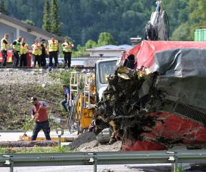 La policía y los trabajadores se ven cerca de un vagón de tren volcado durante los trabajos de rescate en el lugar del descarrilamiento de un tren cerca de Burgrain.