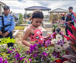 La imagen muestra la visita de Julia López, de nueve años, a la tumba de su padre, Juan López, un defensor ambiental hondureño.