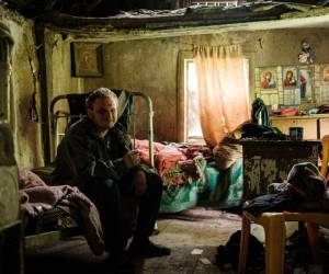 Un hombre posa mientras visita a su madre en su casa sin electricidad, suministro de agua y red telefónica en Lysychansk, este de Ucrania.