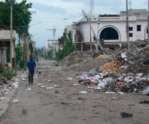 Un hombre camina por una calle del centro este sábado, mientras continúa la búsqueda de cuatro militares salvadoreños integrantes de la Fuerza de Supresión de Pandillas (GSF, sigla en inglés) desaparecidos tras sufrir una emboscada, en Puerto Príncipe (Haití).