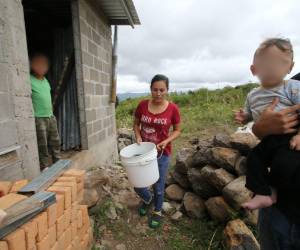 Liliana Aguiluz traslada agua en un balde plástico hacia su pila improvisada con piedras en las afueras de su vivienda, una escena que se repite en las periferias de la capital.