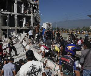 Las personas caminan sobre los escombros de un edificio colapsado este lunes, en Cali (Colombia). Al menos 20 edificios sufrieron graves daños por consecuencia del terremoto.