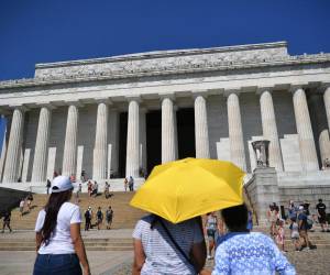 Los visitantes del Lincoln Memorial usan un paraguas para protegerse del sol en Washington.
