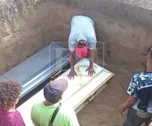 Con sus manos sobre uno de los féretros y todo el peso del dolor en su pecho, un familiares llora en la fosa donde son depositados los ataudes de las tres hermanas.