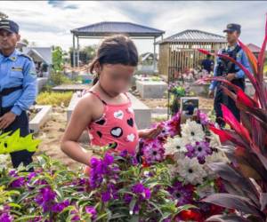 La imagen muestra la visita de Julia López, de nueve años, a la tumba de su padre, Juan López, un defensor ambiental hondureño.