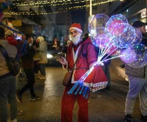 Un hombre vestido como Papá Noel sostiene globos este miércoles, durante las celebraciones navideñas en Lakatia (Siria). Los cristianos de Siria celebran el nacimiento de Cristo un año después de que Bashar Assad huyera y la oposición siria tomara el control del país.