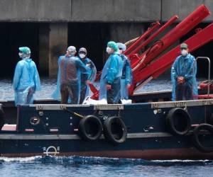 Una vez inspeccionados, los pasajeros abandonaron el crucero con mascarillas y un traje de protección sanitaria en unos barcos más pequeños.