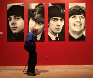 Una persona camina frente a retratos de los integrantes de la banda británica The Beatles durante la exposición 'Ojos de la tormenta', en el Museo de Brooklyn, en Nueva York, en 2024.