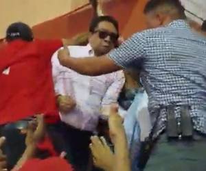 Con empujones y hasta puñetazos, militantes de Libre intentan sacar al diputado Ramón Barrios del estrado principal.