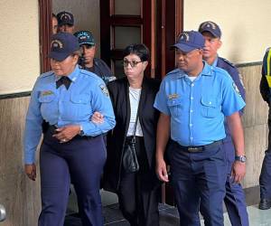 Policías custodian a Maribel Espaillat a su llegada a la sala de audiencias el viernes en Santo Domingo.