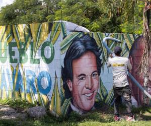 Un ciudadano realiza labores de limpieza frente a un mural con los rostros de los artistas Julio Iglesias y Johnny Ventura en Punta Cana.