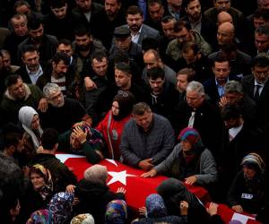 La mujer de Saban abraza su féretro cubierto con la bandera nacional y su retrato.