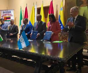 El canciller Enrique Reina y la ministra de Finanzas, Rixi Moncada al momento de la firma de Honduras como nuevo miembro pleno del CAF.