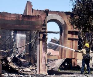 Un bombero trabaja para apagar puntos críticos en una de las más de 20 casas destruidas por el incendio costero el 12 de mayo de 2022 en Laguna Niguel, California.