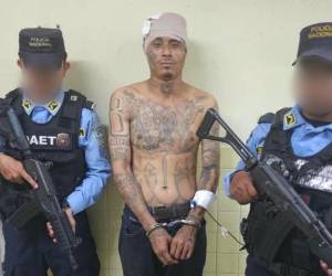 Oliver Alexander Hawkings Omier, conocido con el alias del Astuto; custodiado por dos agentes policiales.