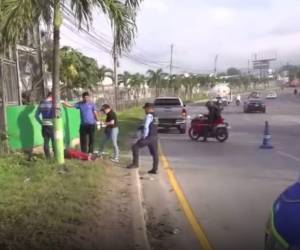 Agentes observan el cadáver de la fémina tendido sobre la acera.