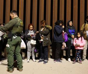 Los inmigrantes que buscan asilo en los Estados Unidos hacen fila mientras son procesados por agentes de la Patrulla Fronteriza.