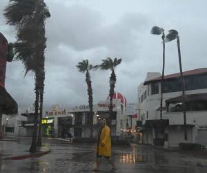 Un hombre camina por una calle en Cabo San Lucas, estado de Baja California, México, mientras la lluvia y las ráfagas de viento del huracán Hilary llegan a la zona, el 19 de agosto de 2023.