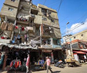Un hombre camina afuera de una tienda de ropa a lo largo de un callejón en el campamento de Shatila para refugiados palestinos en el suburbio sur de Beirut el 7 de noviembre de 2023 en medio de batallas en curso entre Israel y el grupo militante palestino Hamás en la Franja de Gaza.