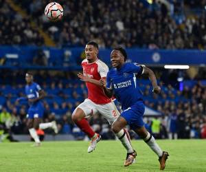 El mediocampista inglés del Chelsea #07 Raheem Sterling (R) y el defensor francés del Arsenal #02 William Saliba (C) persiguen el balón durante el partido de fútbol de la Premier League inglesa entre Chelsea y Arsenal en Stamford Bridge en Londres el 21 de octubre de 2023.