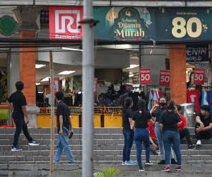 Los empleados de una tienda esperan afuera del edificio en Denpasar, en la isla turística de Bali, luego de que se registrara el terremoto de magnitud 7.0 en el mar al norte de la principal isla indonesia de Java.