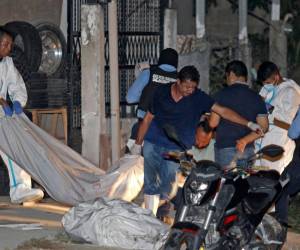 Personal forense retira los cuerpos de once personas muertas en un salón de billar en Choloma, a unos 180 km al norte de Tegucigalpa, el 25 de junio de 2023.
