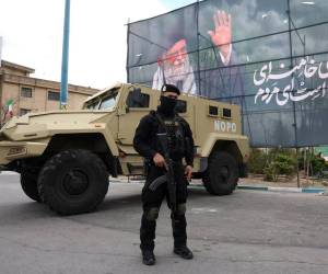Un miembro de las fuerzas de seguridad iraníes monta guardia junto a una pancarta en honor al exlíder supremo iraní Ali Jamenei, en Teherán, Irán.