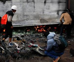 Trabajadores de supermercados inspeccionan los daños causados por el fuego después de que estallaron enfrentamientos entre la policía antidisturbios y manifestantes antigubernamentales en Puno, Perú, el 9 de enero de 2023.