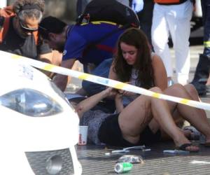 Las personas heridas son tratadas en Barcelona el jueves 17 de agosto de 2017 después de que una furgoneta blanca saltó por la acera en el histórico distrito de Las Ramblas, chocando contra una multitud de turistas y turistas, hiriendo a varias personas, dijo la policía.