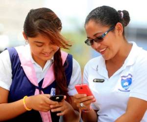 Dos adolescentes conectan sus dispositivos celulares a través de la red inalámbrica.