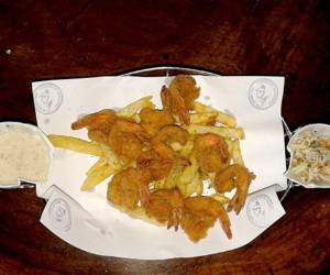 Camarones empanizados, con salsa tártara, papas fritas y ensalada a base de repollo.