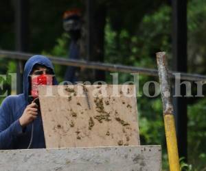 Uno de los estudiantes se protege con una tabla para evitar el chorro de agua lanzado por la tanqueta de la Policía Nacional. Foto: Emilio Flores/El Heraldo.