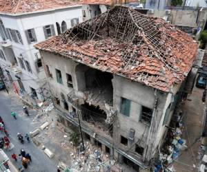 La gente pasa frente a una casa que resultó dañada durante la explosión de la semana pasada que golpeó el puerto marítimo de Beirut, Líbano. Foto AP.