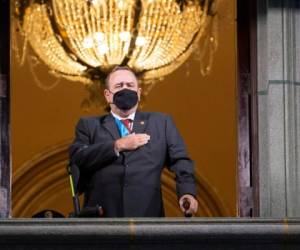 El presidente de Guatemala, Alejandro Giammattei, con una mascarilla protectora como precaución contra la propagación del nuevo coronavirus, canta el himno nacional durante la celebración del día de la independencia en la Ciudad de Guatemala. Foto AP.