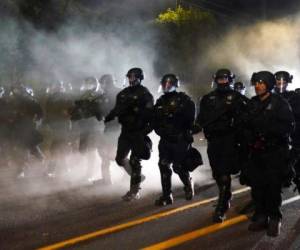 Los agentes de la policía de Portland avanzan por el vecindario de Laurelhurst después de dispersar a manifestantes de la Oficina del Sheriff del condado Mulnomah. Foto AP.