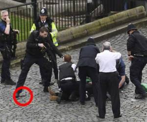 Un oficial apunta al atacante del Parlamento británico, al tiempo que aplasta con su pie el arma blanca que tenía el agresor (AP)