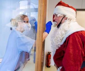 Tessa Boulton, a la izquierda, toma una muestra a Michael Kruse, vestido como Santa Claus, en un centro de pruebas de virus en la clínica Helios de Schwerin, Alemania. Tras este año de incertidumbre y caos de pandemia, todo lo que quería la mayoría de la gente por Navidad era algo de alegría y reuniones. Foto: AP.