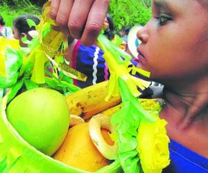 Una niña muestra orgullosa una canasta llena de frutas en el desfile.