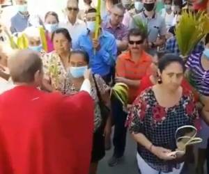 El sacerdote hondureño durante la procesión del Domingo de Ramos mientras le quitaba la mascarilla a una feligrés. Foto: Captura de video.