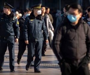Un agente de seguridad utiliza un cubrebocas mientras vigila afuera de la estación de trenes en Beijing el lunes 20 de enero de 2020.