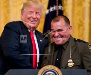 El presidente Donald Trump recibe al agente de la Patrulla Fronteriza Adrian Azaldua en el escenario para hablar durante un evento de reconocimiento a los agente del Servicio de Control de Inmigración y Aduanas y la Oficina de Aduanas y Protección Fronteriza en la Sala Este de la Casa Blanca el lunes 20 de agosto de 2018 en Washington.
