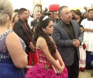 La quinceañera junto a su padre en la misa de celebración para iniciar el evento.