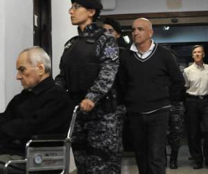 El cura italiano Nicola Corradi y el padre argentino Horacio Corbacho, seguido por el jardinero Armando Gomez son llevados de la corte tras escuchar el veredicto. Foto: AFP.