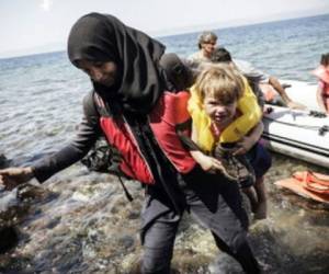 Una mujer siria con su hijo llega a la isla griega de Lesbos, después de cruzar el mar Ego en un bote inflable desde Turquía.
