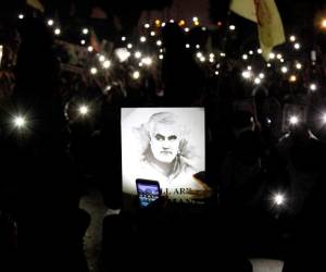 Una persona ilumina un retrato del fallecido general iraní Qassem Soleimani con la lámpara de un teléfono, en Karachi, Pakistán, el domingo 5 de enero 2020. (AP Foto/Ikram Suri)