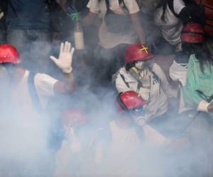 Los trabajadores de Heath son vistos a través de gases lacrimógenos lanzados por la Guardia Nacional para evitar que manifestantes antigubernamentales se reúnan en la Plaza Altamira en Caracas para protestar contra el presidente venezolano Nicolás Maduro.