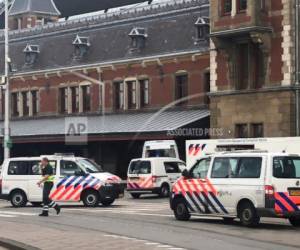 Vehículos de la policía holandesa rodean la estación central del ferrocarril en Amsterdam, el viernes 31 de agosto de 2018, luego de que dos personas resultaron lesionadas a puñaladas por un sospechoso que fue herido a disparos.